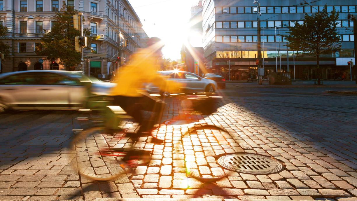 Pyöräilijä ajaa Mannerheimintiellä Helsingissä. Taustalla menee autoja.