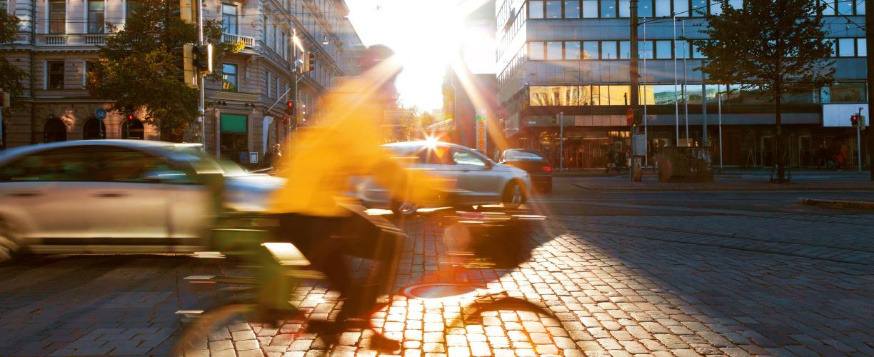 Pyöräilijä ajaa Mannerheimintiellä Helsingissä. Taustalla menee autoja.