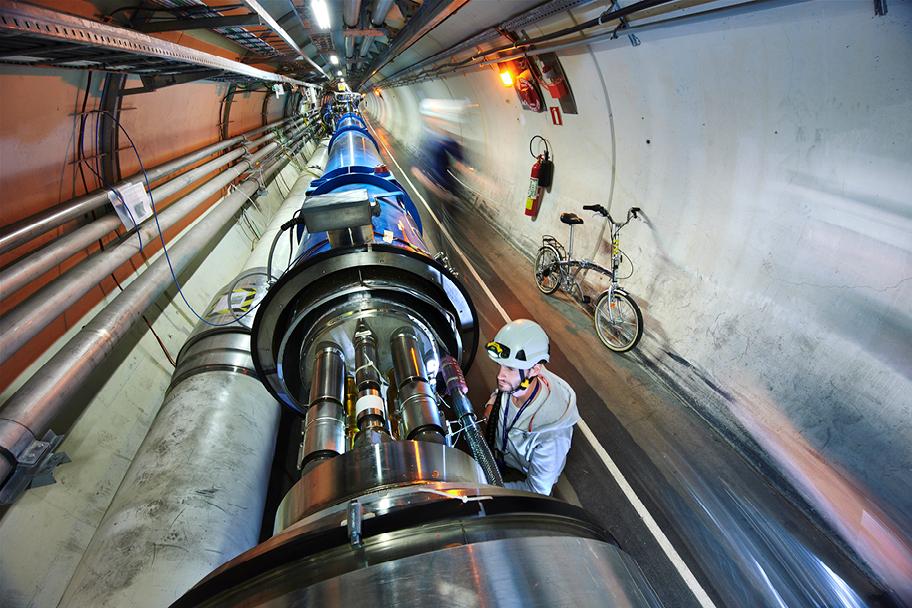 Kypäräpäinen ihminen tutkii CERNin hiukkaskiihdytintä pitkässä tunnelissa..